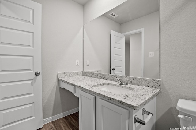 bathroom with hardwood / wood-style floors, vanity, and toilet