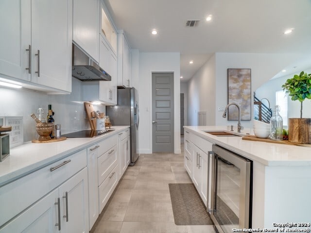 kitchen featuring black electric cooktop, light tile patterned floors, beverage cooler, ventilation hood, and sink