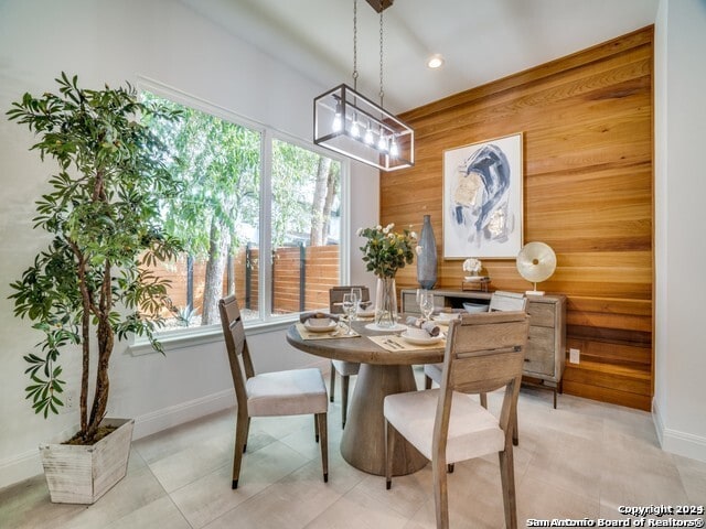 dining space with wood walls and light tile patterned floors