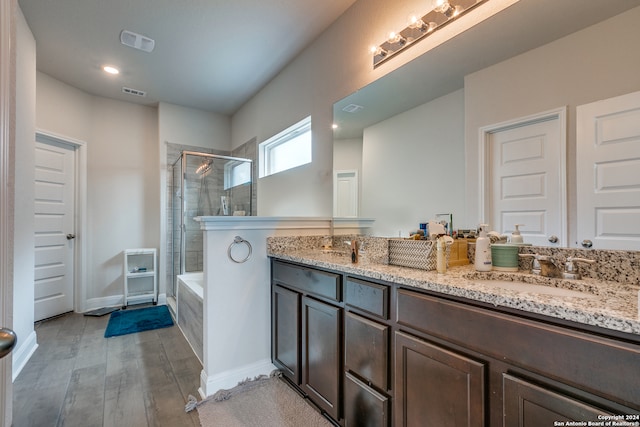 bathroom with shower with separate bathtub, dual vanity, and wood-type flooring