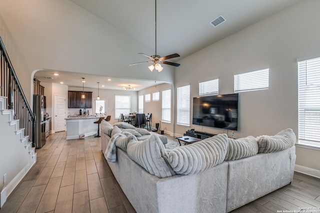 living room featuring light hardwood / wood-style flooring, high vaulted ceiling, and ceiling fan