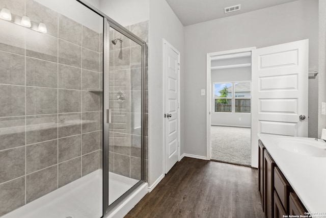 bathroom with walk in shower, vanity, and hardwood / wood-style flooring