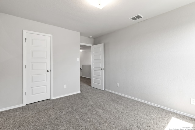 unfurnished bedroom with dark colored carpet and a closet