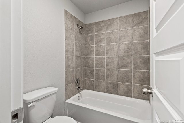 bathroom with tiled shower / bath combo and toilet