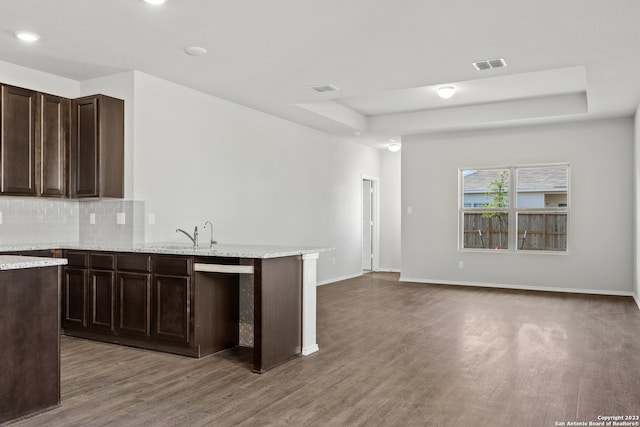 kitchen featuring dark brown cabinetry, a raised ceiling, sink, tasteful backsplash, and hardwood / wood-style flooring