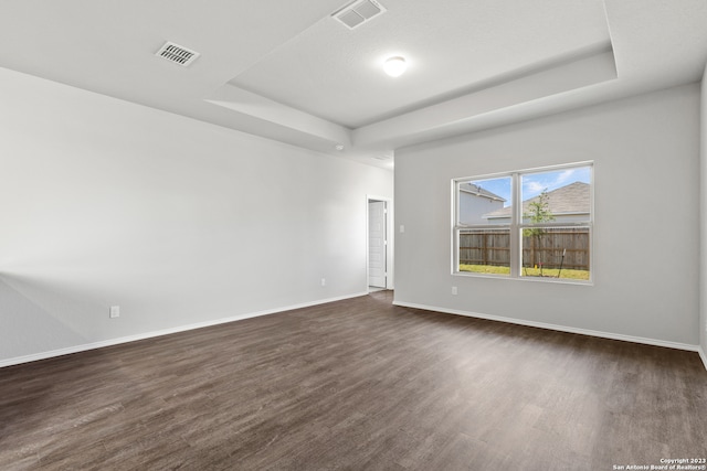 unfurnished room featuring a tray ceiling and dark hardwood / wood-style floors