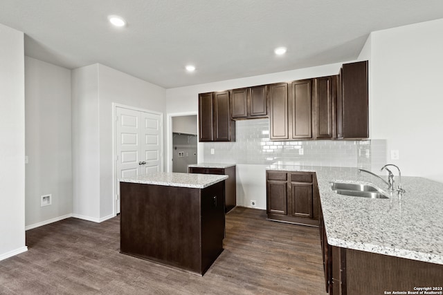 kitchen with a kitchen island, sink, dark wood-type flooring, and tasteful backsplash