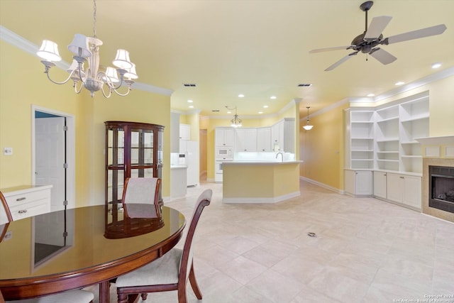 dining space with ornamental molding, sink, and ceiling fan with notable chandelier