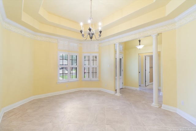 spare room with ornate columns, a tray ceiling, and an inviting chandelier