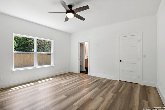 unfurnished bedroom with connected bathroom, ceiling fan, and light hardwood / wood-style flooring