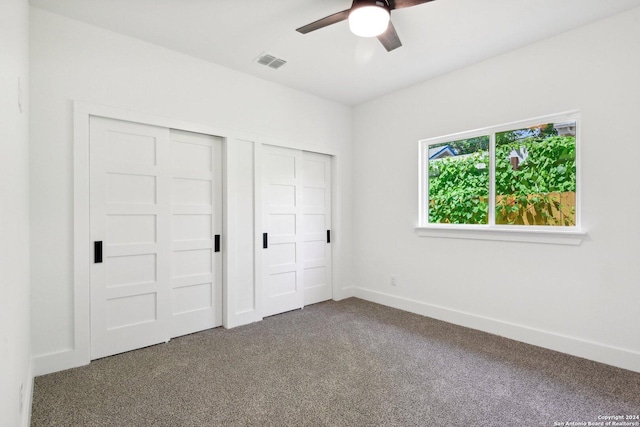 unfurnished bedroom featuring ceiling fan, carpet floors, and two closets