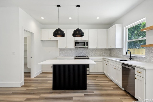 kitchen featuring sink, a center island, decorative light fixtures, white cabinets, and appliances with stainless steel finishes