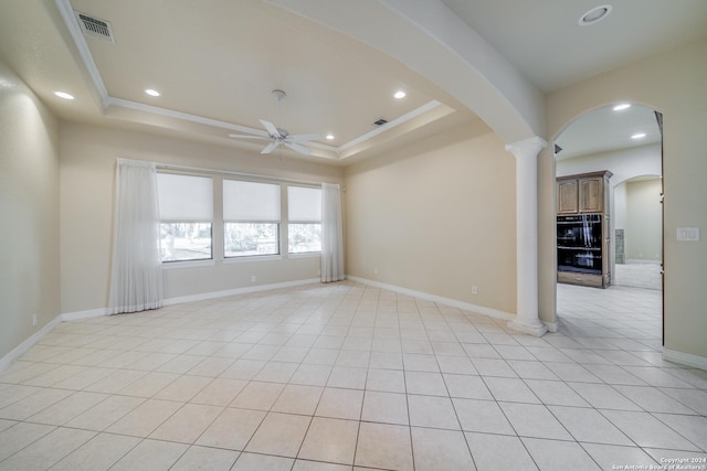 spare room featuring ceiling fan, decorative columns, light tile patterned floors, and a tray ceiling