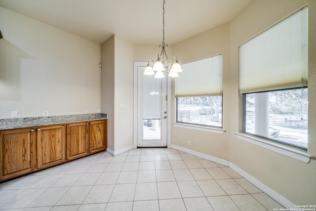 unfurnished dining area with light tile patterned floors and an inviting chandelier