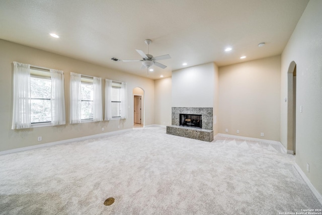 unfurnished living room featuring ceiling fan, a high end fireplace, and light colored carpet