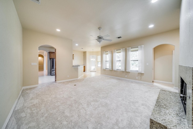 unfurnished living room featuring ceiling fan, light carpet, and a brick fireplace