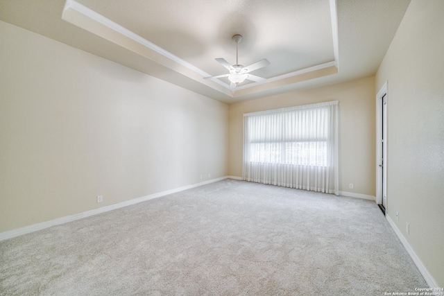 carpeted empty room with a raised ceiling and ceiling fan