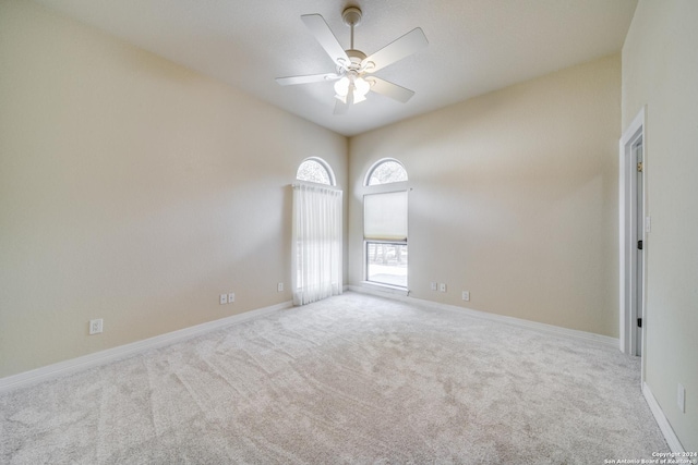 empty room with ceiling fan, light colored carpet, and lofted ceiling