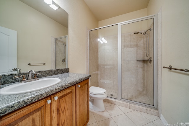 bathroom featuring toilet, vanity, tile patterned floors, and a shower with door