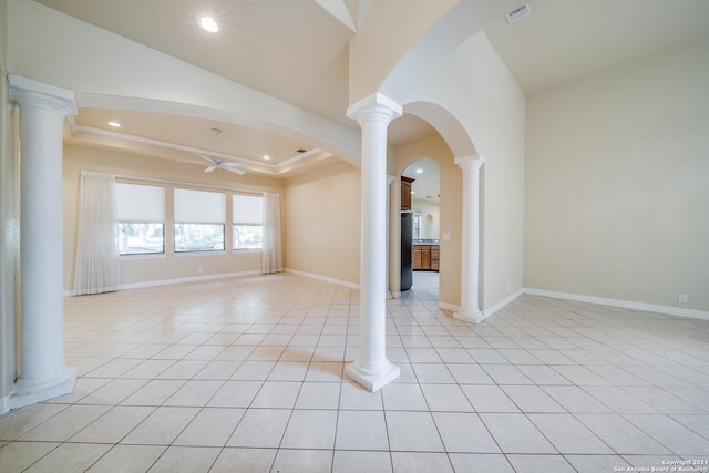 empty room with light tile patterned floors, decorative columns, and ceiling fan