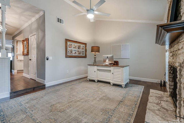 home office featuring ceiling fan, dark hardwood / wood-style floors, ornamental molding, and a stone fireplace