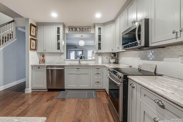 kitchen with dark hardwood / wood-style flooring, sink, decorative light fixtures, appliances with stainless steel finishes, and light stone counters