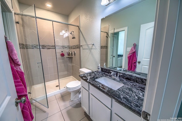 bathroom with walk in shower, vanity, tile patterned flooring, and toilet