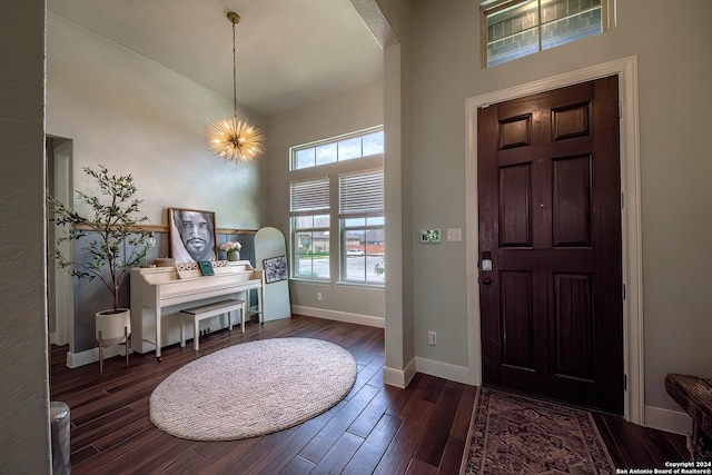 foyer entrance with a high ceiling, dark hardwood / wood-style floors, and a notable chandelier