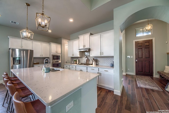 kitchen featuring hanging light fixtures, white cabinets, a kitchen island with sink, and stainless steel appliances