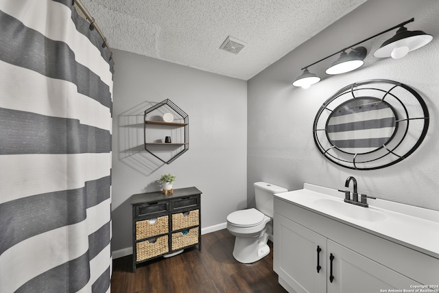 bathroom with hardwood / wood-style flooring, toilet, vanity, and a textured ceiling