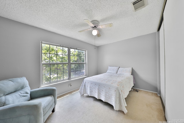 carpeted bedroom featuring a textured ceiling and ceiling fan