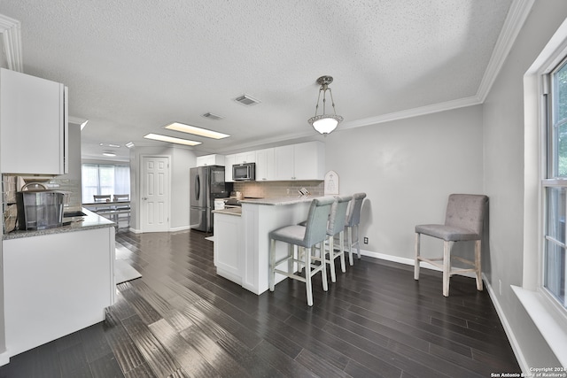 kitchen with tasteful backsplash, hanging light fixtures, white cabinets, stainless steel refrigerator, and dark wood-type flooring