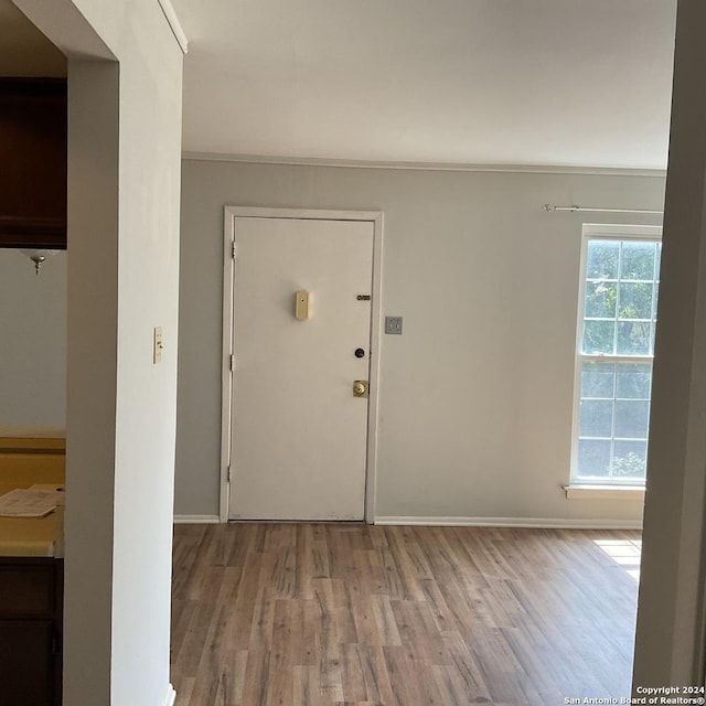 foyer featuring a wealth of natural light, crown molding, and light hardwood / wood-style floors