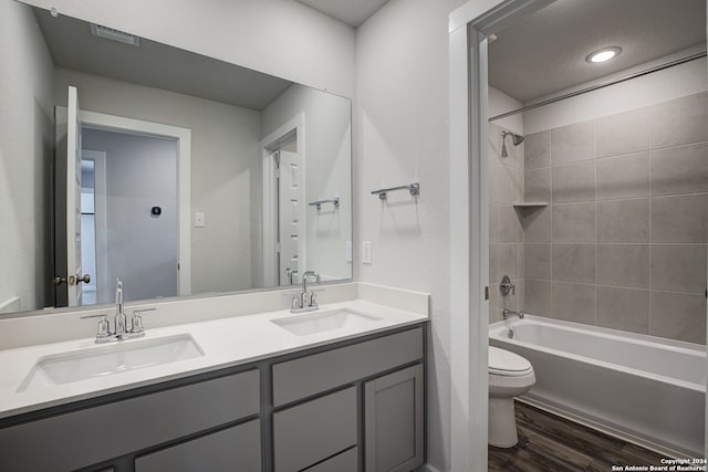 full bathroom with vanity, toilet, wood-type flooring, and tiled shower / bath