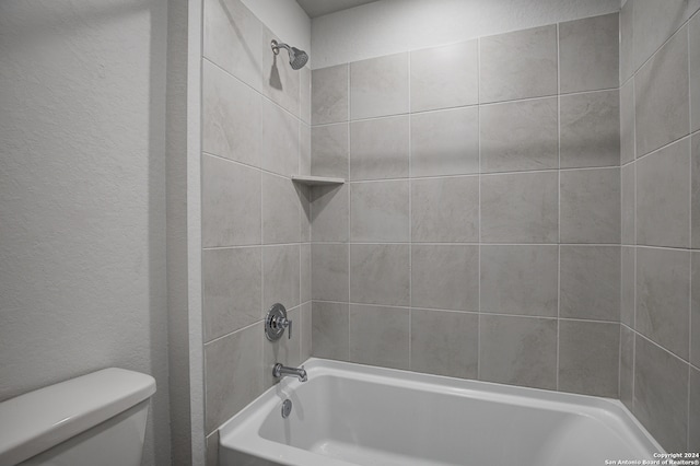 bathroom with tiled shower / bath combo and toilet