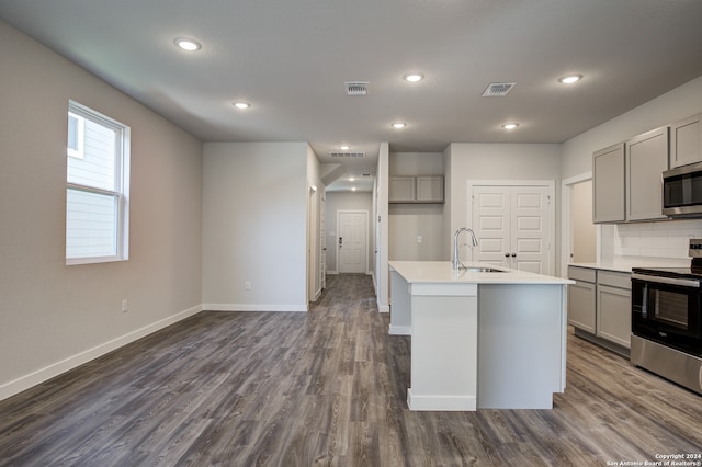 kitchen with gray cabinetry, a center island with sink, stainless steel appliances, and dark hardwood / wood-style floors