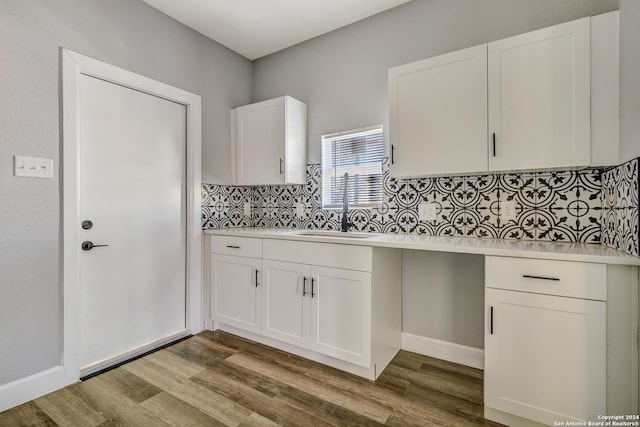 kitchen with light wood-type flooring, white cabinetry, and sink