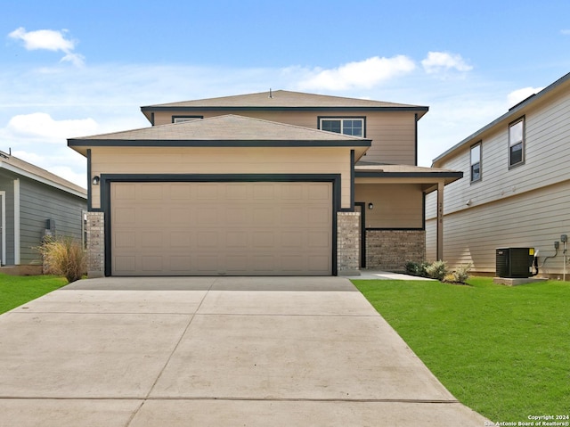 view of front of house with cooling unit, a garage, and a front yard