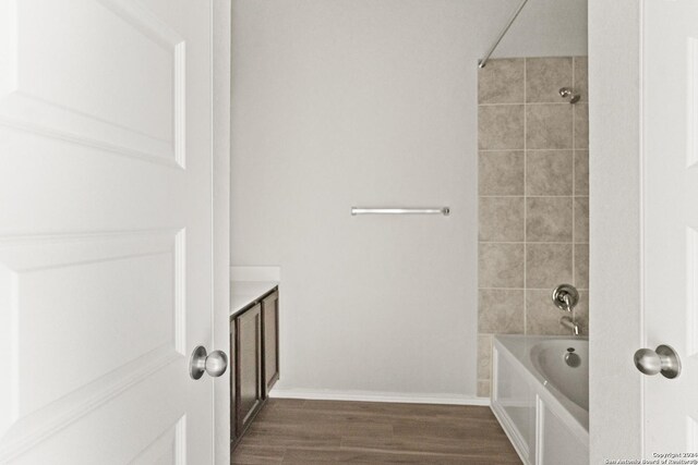 bathroom with hardwood / wood-style flooring and tiled shower / bath