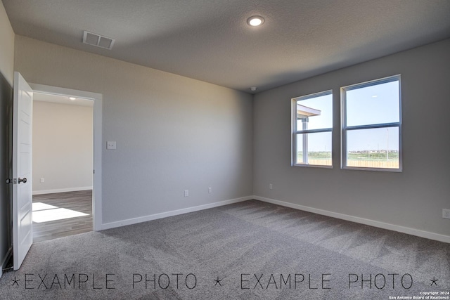 unfurnished room featuring a textured ceiling and carpet flooring