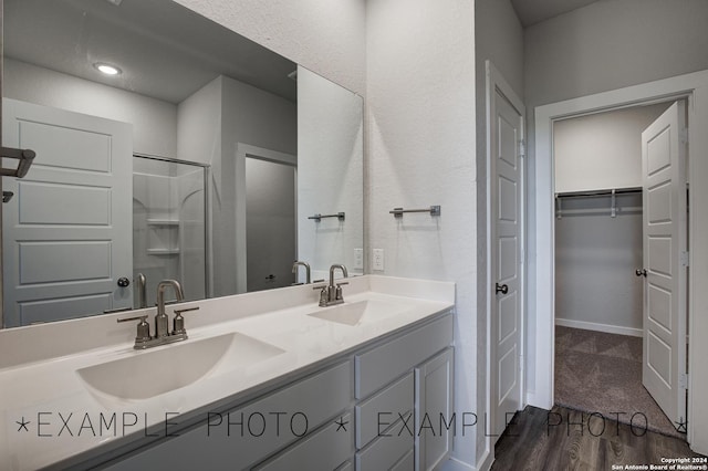 bathroom with walk in shower, vanity, and hardwood / wood-style floors