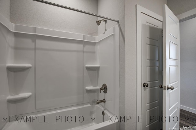 bathroom featuring a textured ceiling, shower / tub combination, and hardwood / wood-style flooring