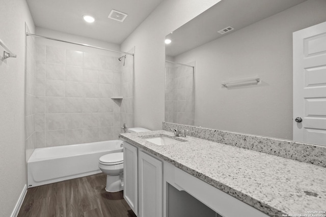 full bathroom featuring toilet, vanity, hardwood / wood-style floors, and tiled shower / bath