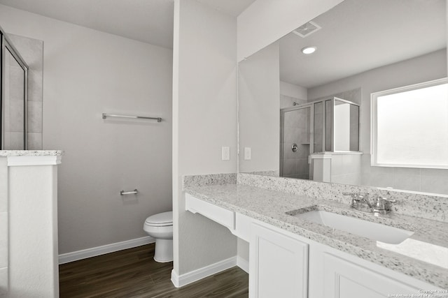 bathroom featuring toilet, vanity, a shower with shower door, and hardwood / wood-style flooring