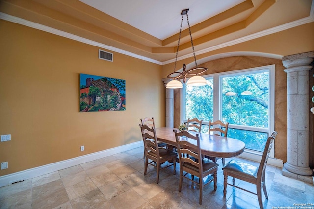 dining room with crown molding, a raised ceiling, and ornate columns