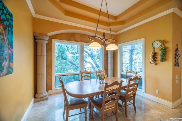 dining area featuring ornamental molding, a raised ceiling, and ornate columns