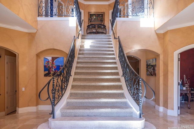 staircase with a towering ceiling and ornamental molding