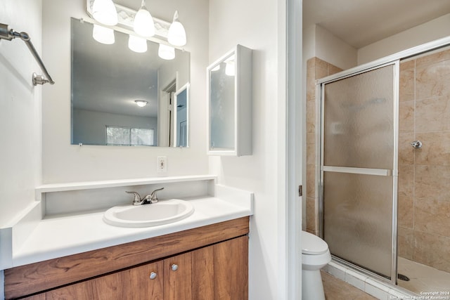 bathroom featuring tile patterned floors, toilet, a shower with door, and vanity