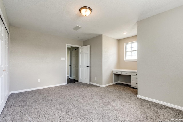 unfurnished bedroom with a textured ceiling, a closet, and carpet