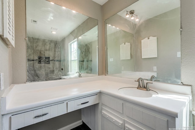 bathroom featuring tiled shower and vanity